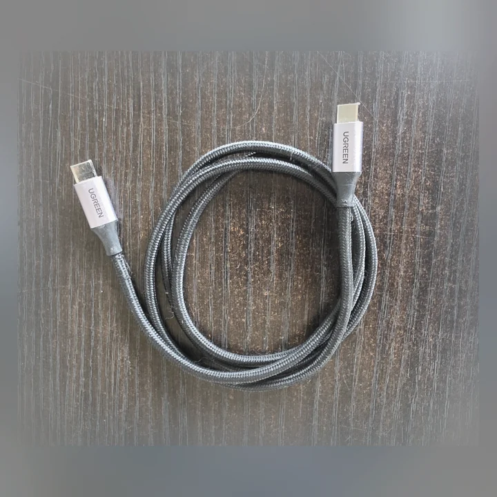 Flätad USB-C-kabel från UGREEN, hoprullad på ett bord.